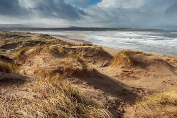 Fototapeta na wymiar View on Strandhill beach, county Sligo, Ireland. Sandy dunes and cloudy sky. Warm sunny day, Nobody. Atlantic ocean on the right.