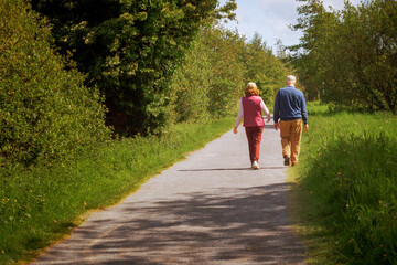 Fototapeta premium Old couple walking on a foot path on a warm sunny day. Concept active lifestyle.