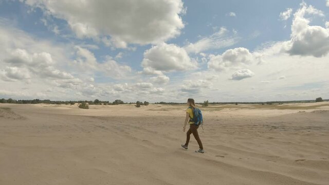 Young girl hiking in dunes. Slow motion. Sports, healthy lifestyle, isolation, travel concept.