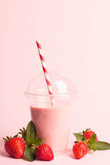 Glass of fresh strawberry milkshake, smoothie and fresh strawberries on pink, white and wooden background. Healthy food and drink concept.
