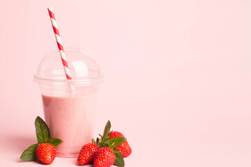 Glass of fresh strawberry milkshake, smoothie and fresh strawberries on pink, white and wooden...