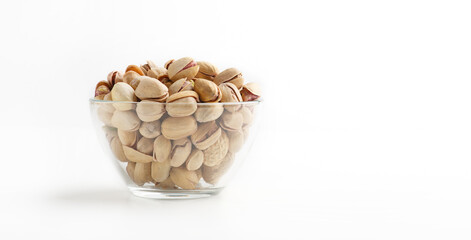 Delicious food for evening with beer. Glass plate with pistachios on white background