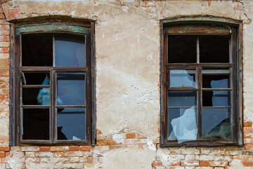 Fototapeta na wymiar Two window frames with broken glasses in an old abandoned brick house