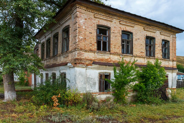 Fototapeta na wymiar An old abandoned brick building overgrown with trees