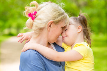 Fototapeta premium Mother and little girl with syndrom down have a fun in summer park