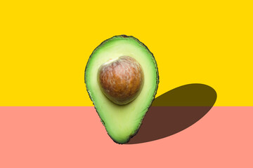 Raw ripe halved avocado with pit imitating map pointer with drop shadow on duo tone yellow pink background. Creative food poster banner for vegan healthy oil diet concept