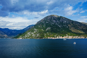 View of the mountain lake, mountains, pleasure yachts. An island in the middle of the lake. The famous fjord-like bay, on the rocky shores of which Kotor and Perast are located. Boko Kotor bay, cove.