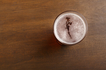 Craft beer in pub. Drink with foam in glass on brown wooden table