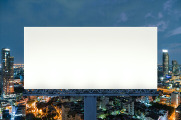 Blank white road billboard with Bangkok cityscape background at night time. Street advertising poster, mock up, 3D rendering. Front view. The concept of marketing communication to promote idea.