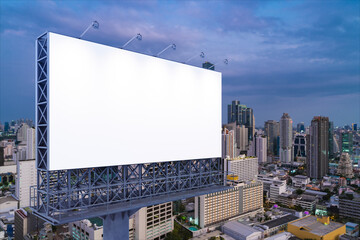 Obraz premium Blank white road billboard with Bangkok cityscape background at night time. Street advertising poster, mock up, 3D rendering. Side view. The concept of marketing communication to sell idea.