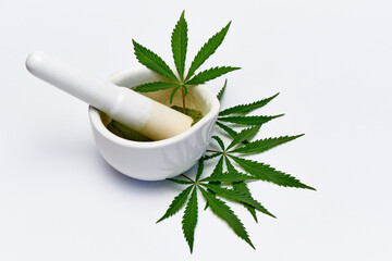 Mortar with powder and cannabis leaves on a white background.