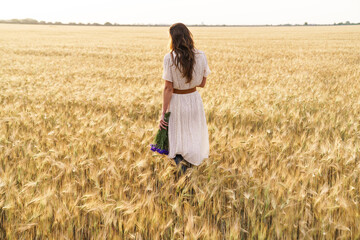 Photo of beautiful cute woman posing while walking on wheat field