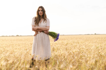 Photo of beautiful cute woman posing while walking on wheat field