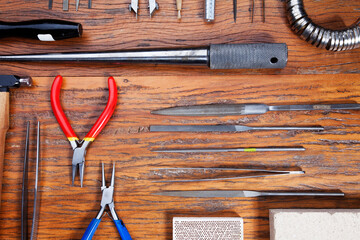 Different goldsmiths tools on the jewelry workplace. Desktop for craft jewelry making with professional tools.