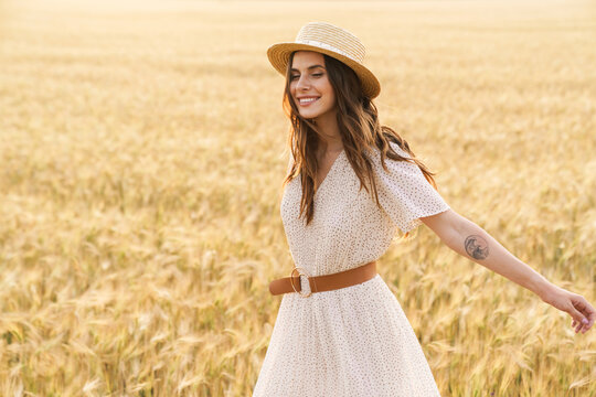 Photo of beautiful happy woman smiling and walking on wheat field