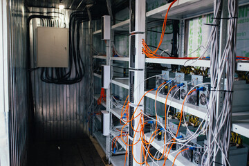 ASIC miners stand on a shelf and connected to electricity and the Internet