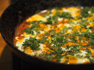 Image of fried eggs in a pan with tomatoes and herbs. Healthy summer natural food.