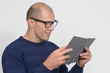 Portrait of young bald nerd man reading book