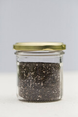 organic chia seeds in glass jar on gray background.