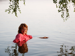 beautiful girl bathes in a lake at sunset