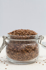 organic flax seeds in glass jar on gray background.