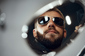 Reflection in the motorcycle mirror of a man driver in sunglasses