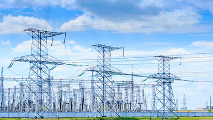 pylons of high voltage electric lines against a background of blue sky and white clouds