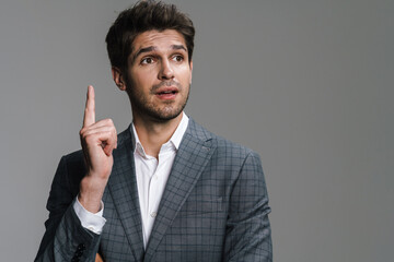 Photo of unshaven surprised businessman pointing finger upward
