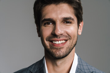 Photo of pleased businessman in jacket posing and smiling at camera