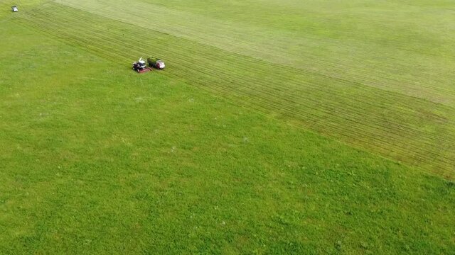 Aerial photography. Wide and close-up shots of a harvester cutting green grass. The concept of sustainable biofuels and organic food.