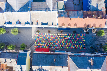 multi-colored umbrellas hang in the air on a narrow ancient street of the city