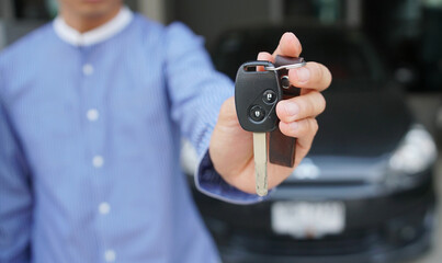 Man holding car keys with car