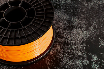 Filament for 3d printing. Bright thermoplastic of neon orange, color. Reel horizontal view.