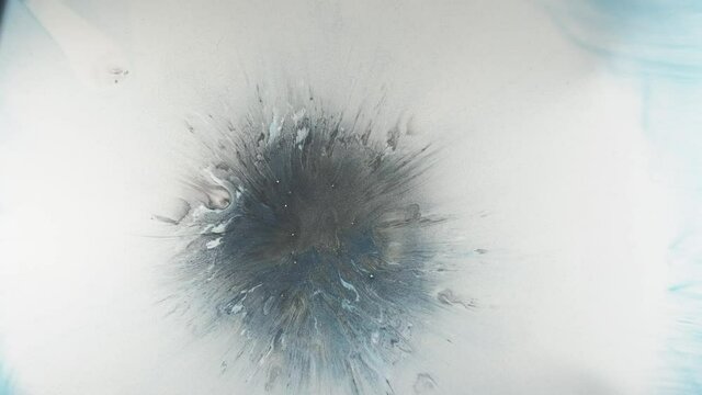 Paint splash in water. Hypnotic motion. Dark ink drop splatter spreading in blue white glitter fluid.