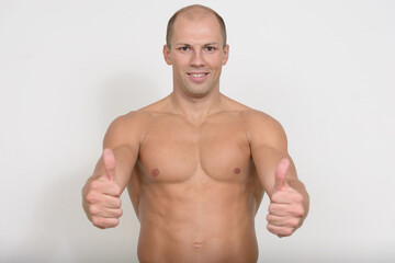 Fototapeta premium Happy young muscular bald man giving thumbs up shirtless