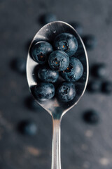 Metal spoon whit blueberries on a dark base. Close up.