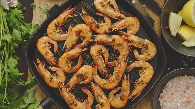 Roasted tiger prawns on iron grilling pan with fresh persley, lemon, chilli and bread