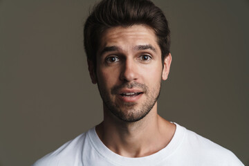 Fototapeta premium Portrait of surprised young man in basic t-shirt posing on camera