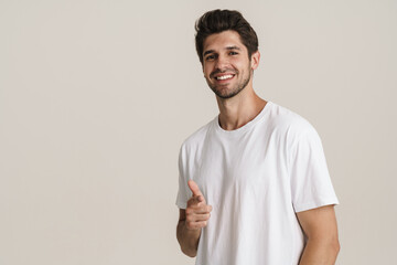 Portrait of joyful young man smiling and pointing finger at camera