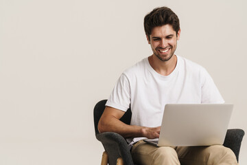 Portrait of laughing man working with laptop while sitting on armchair