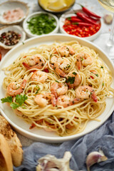 Spaghetti with shrimps on white ceramic plate and served with glass of white wine