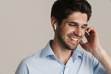Portrait of cheerful man laughing while using wireless earphone
