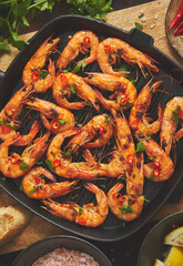 Roasted tiger prawns on iron grilling pan with fresh persley, lemon, chilli and bread