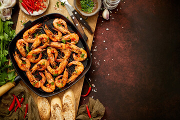 Tasty appetizing roasted shrimps prawns with spices on pan with ingredients on rusty background