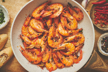 Traditional fried tiger prawn with garlic bread as top view served in a white frying pan