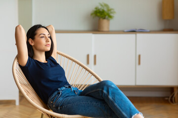 Relaxed Woman Sitting Holding Hands Behind Head In Chair Indoor