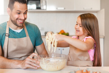 Father And Daughter Baking Together Playing Kneading Dough Sitting Indoors