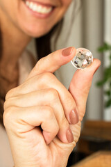 Woman smiling holding a diamond stone. Goldsmiths tools on the jewelry workplace. 