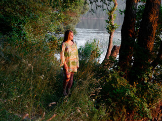 beautiful girl in a green bush at sunset