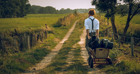Musician with handcart, loaded with instruments, walking on a romantic trail